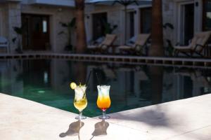 two drinks sitting on a table next to a swimming pool at İcarus Alaçatı in Çeşme