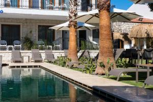 a pool with chairs and umbrellas next to a building at İcarus Alaçatı in Çeşme