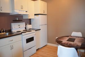 a small kitchen with white appliances and a table at Le Citadin in Rouyn