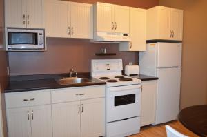 a kitchen with white appliances and white cabinets at Le Citadin in Rouyn