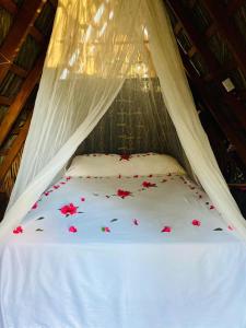 Una cama blanca con flores rojas. en Bungalows Tukitlan en Zihuatanejo