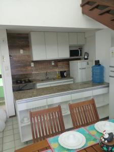 uma cozinha com armários brancos e uma mesa e cadeiras em Flat no ancorar flat resort em Porto de Galinhas