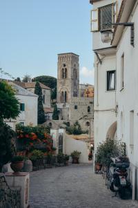 budynek z wieżą i kościołem w tle w obiekcie Il Centro Storico Ravello w mieście Ravello