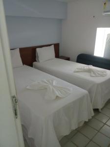 duas camas num quarto de hotel com lençóis brancos em Flat no ancorar flat resort em Porto de Galinhas