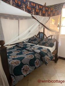 1 dormitorio con 1 cama con dosel en Wimbi Cottage, en Nungwi