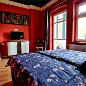 a bedroom with red walls and a bed with a blue blanket at Fewo LILY in Porschdorf