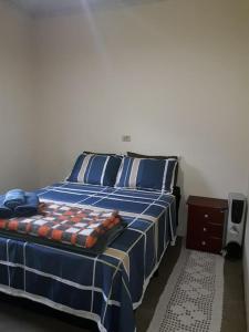 a bedroom with a bed with a blue comforter at Casinha nas montanhas in Gonçalves