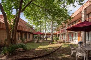 un patio con mesas, sillas y árboles en GreenTree Hotel & Extended Stay I-10 FWY Houston, Channelview, Baytown, en Channelview