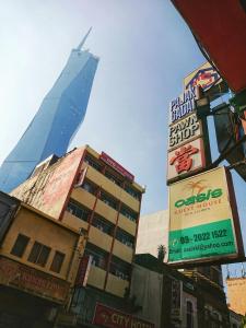 un edificio alto en medio de una ciudad con señales en Oasis Guest House, en Kuala Lumpur