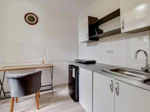 - une cuisine avec des placards blancs, un évier et une table dans l'établissement Deluxe Apartment in Oberhausen with Breakfast, à Oberhausen