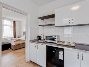 eine Küche mit weißen Schränken und einer Mikrowelle in der Unterkunft Deluxe Apartment in Oberhausen with Breakfast in Oberhausen