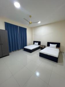 two beds in a room with blue curtains at Evan إيفان in Salalah