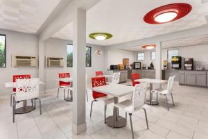 un comedor con mesas blancas y sillas rojas en Super 8 by Wyndham Lenexa Overland Park Area/Mall Area en Lenexa