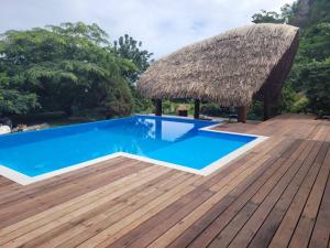 a resort with a blue swimming pool and a thatch roof at Tokoau Uta in Moorea