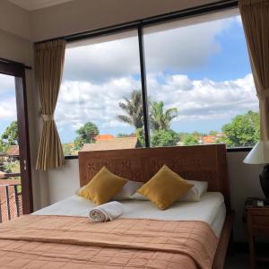a bedroom with a bed and a large window at Run House B&B in Ubud