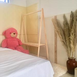 un orsacchiotto rosa seduto sopra un letto di Bảo Châu Garden a Buôn Dru Dak Mam