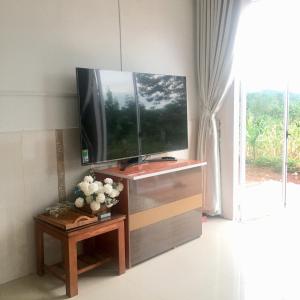 telewizor z płaskim ekranem siedzący na szczycie drewnianego centrum rozrywki w obiekcie Bảo Châu Garden w mieście Buôn Dru Dak Mam