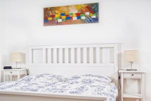 a white bedroom with a bed and two night stands at Vailo City Suites Leipzig Altstadt in Leipzig