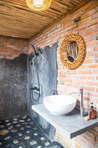 a bathroom with a white sink on a brick wall at ECOZY by Biji Valley in Selat