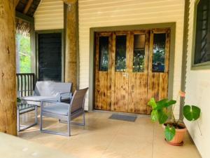 a porch with a table and chairs and a wooden door at Fale Tonga Guesthouse in Puke +2 photos
