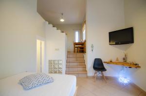 1 dormitorio con 1 cama, TV y silla en Ios stylish house Panoramic Sea and Sunset view, en Ios Chora