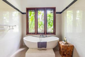 a bath tub in a bathroom with a window at Private Pool Villa - Villa Saia Ubud in Ubud