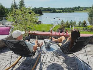 a man and a woman sitting in chairs on a deck at Lavender Inn Guest House in Viešvėnai