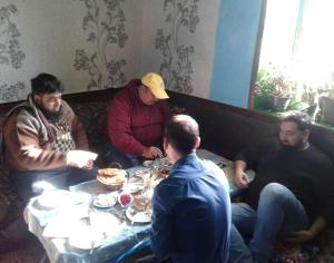 un grupo de hombres sentados alrededor de una mesa comiendo en Ecomama in Xınalıq Khinalig guest house en Quba