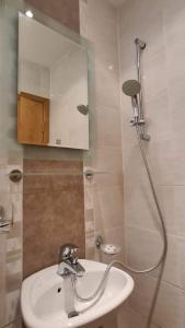 ein Bad mit einem Waschbecken und einer Dusche mit einem Spiegel in der Unterkunft Апартамент Лагуна Aйланд in Sozopol