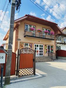 ein Haus mit einem roten Tor und Blumen auf den Balkonen in der Unterkunft U Maksa in Solotschyn