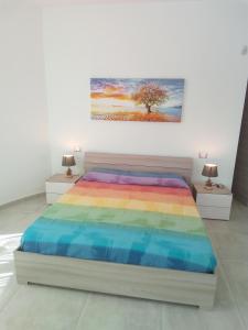 a bedroom with a rainbow bed and a painting on the wall at Villa Anna Maria in Polignano a Mare