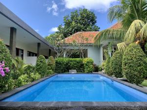 a swimming pool in front of a house at Davit Guesthouse Nusa Dua in Nusa Dua