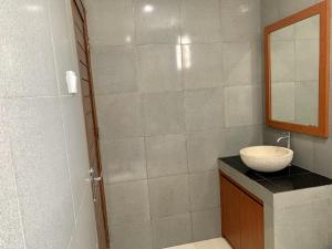 La salle de bains est pourvue d'un lavabo et d'une douche. dans l'établissement Davit Guesthouse Nusa Dua, à Nusa Dua