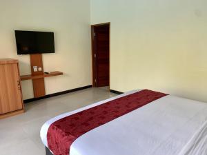 a bedroom with a bed and a flat screen tv at Davit Guesthouse Nusa Dua in Nusa Dua