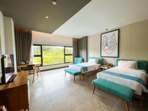 a bedroom with two beds and a desk and a television at Hotel Dafam Wonosobo in Wonosobo