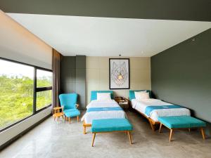 two beds in a room with blue chairs and windows at Hotel Dafam Wonosobo in Wonosobo