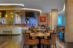 uma sala de jantar com mesas e cadeiras num restaurante em Radisson Gurugram Udyog Vihar em Gurgaon