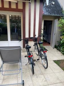 two bikes parked next to a chair in front of a house at Maison vélo piscine tennis in Deauville