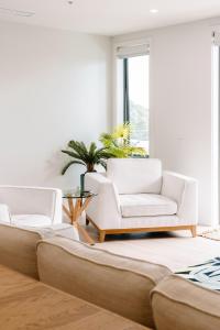 sala de estar con 2 sillas blancas y sofá en Oceanview Retreat en Nelson