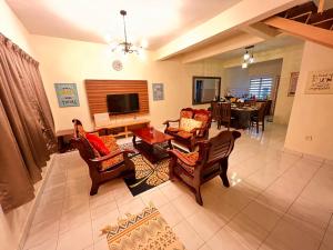 a living room with chairs and a table and a television at The Zonne Home stay Cameron Highlands in Tanah Rata
