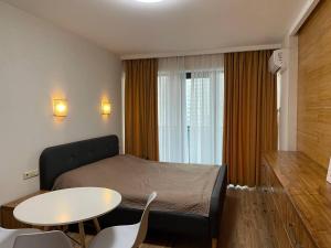 a bedroom with a bed and a table and a window at Coast Batumi Apart Hotel in Batumi