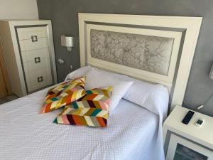una camera da letto con un letto bianco con due cuscini colorati di Apartamento Benalmádena playa a Benalmádena