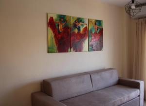 a living room with a couch and three paintings on the wall at Xanthiotis Apartments in Skala Rachoniou