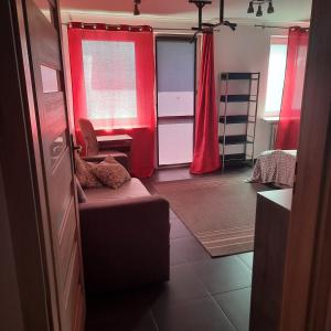a room with red curtains and a couch and a bedroom at Apartament Robotnicza in Sanok