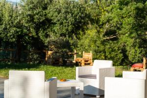 un gruppo di sedie e tavoli bianchi in un cortile di U Saccataro Casa Vacanze a Ogliastro Cilento