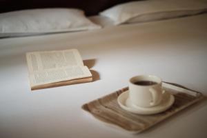 a cup of coffee and a book on a bed at Bononi in Jorhāt