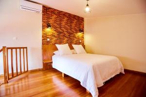 a bedroom with a bed and a brick wall at La Pergola - Appartement Hôtel in Antananarivo