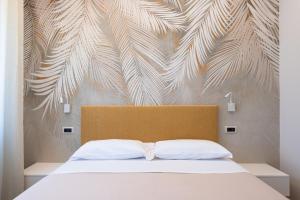 a bedroom with a white bed with a wall with a mural at Albergo Degli Amici in Chieti