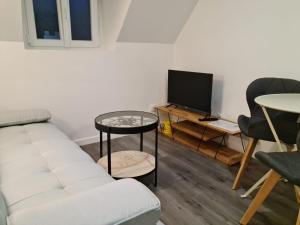 a living room with a white couch and a tv at Beaugency-1 sur la route des Châteaux in Beaugency