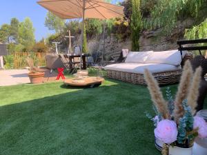 a garden with a couch and an umbrella at Chalet de Luxe Jardin Privatif 3mn Circuit Castellet in Le Beausset